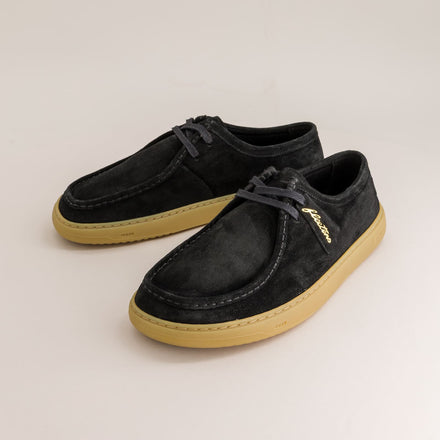 Pair of black suede barefoot derby shoes with tan soles on a light gray background