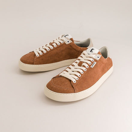Pair of brown minimalist sneakers with white laces on a light gray background
