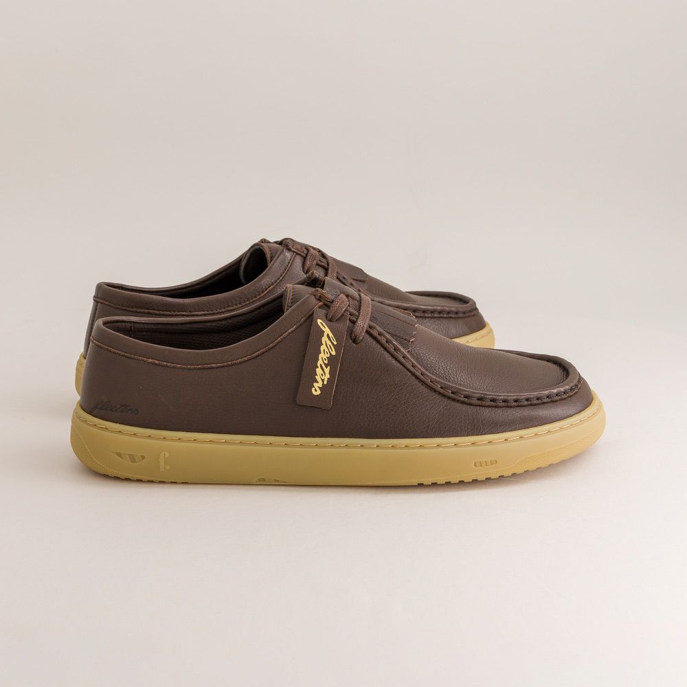 Brown barefoot derbies with a visible brand label on a light gray background