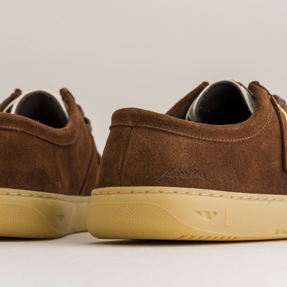 Brown suede barefoot derbies with beige soles on a light gray background