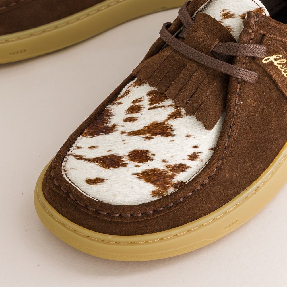 Brown suede barefoot derbies with white cow print insole on a light background