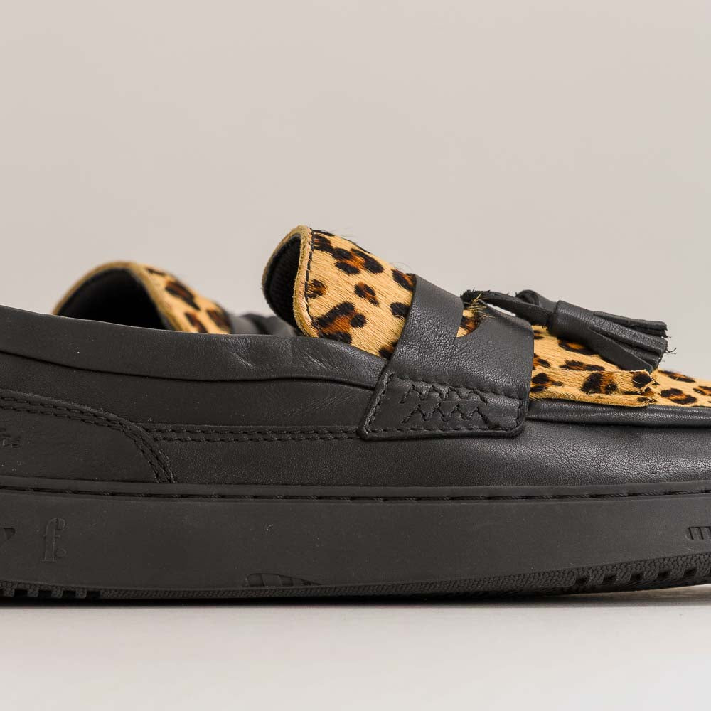 Black barefoot loafer with leopard print strap and tassel on a gray background