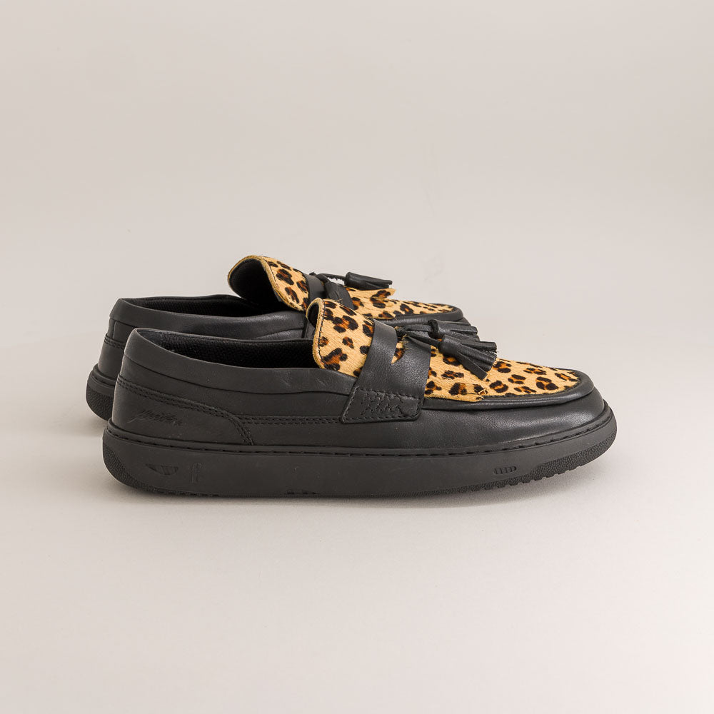 Black barefoot loafers with leopard print accents on a beige background