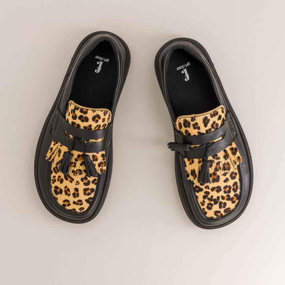 Pair of leopard print mocassins with black straps on a light background