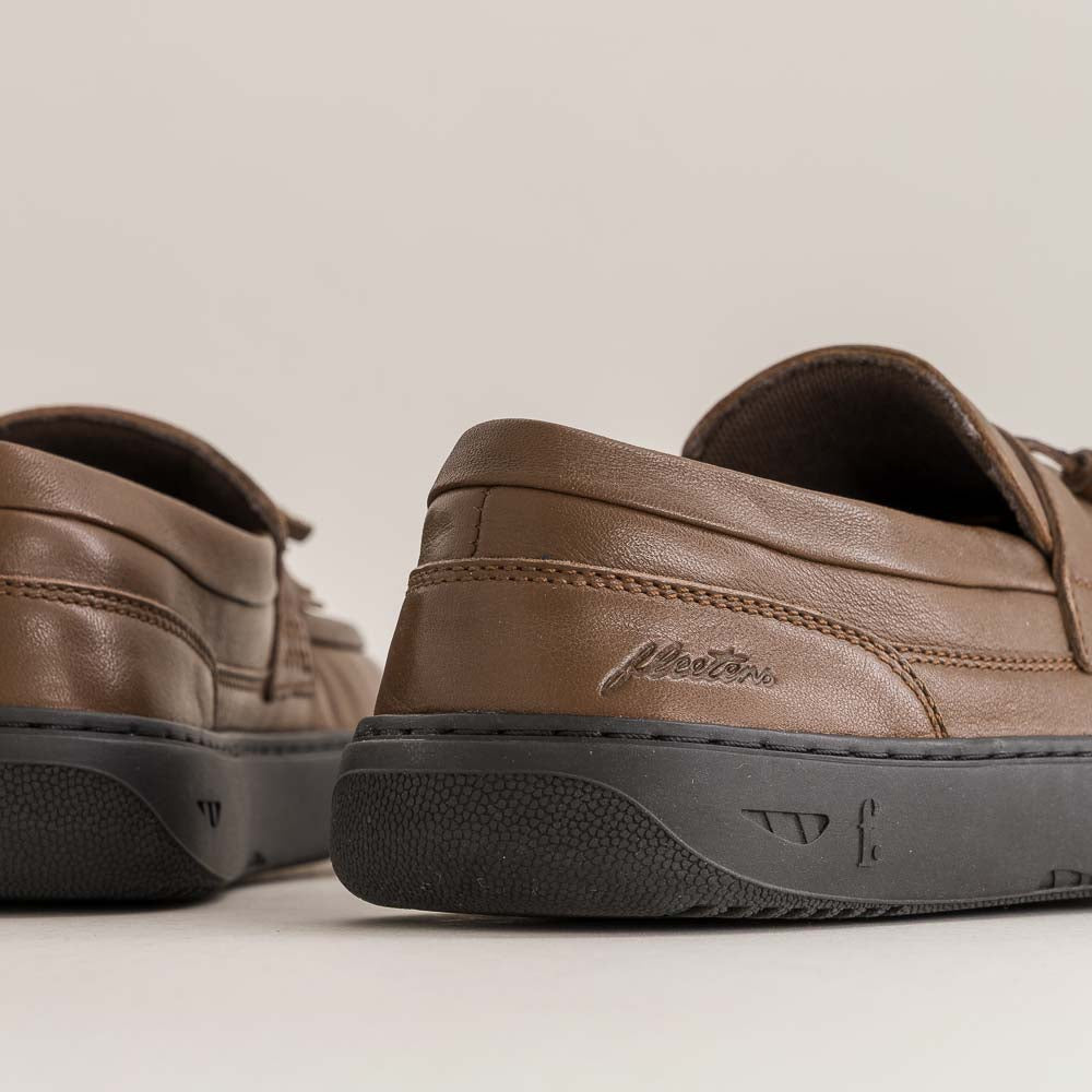 Brown leather shoes with black soles on a light background