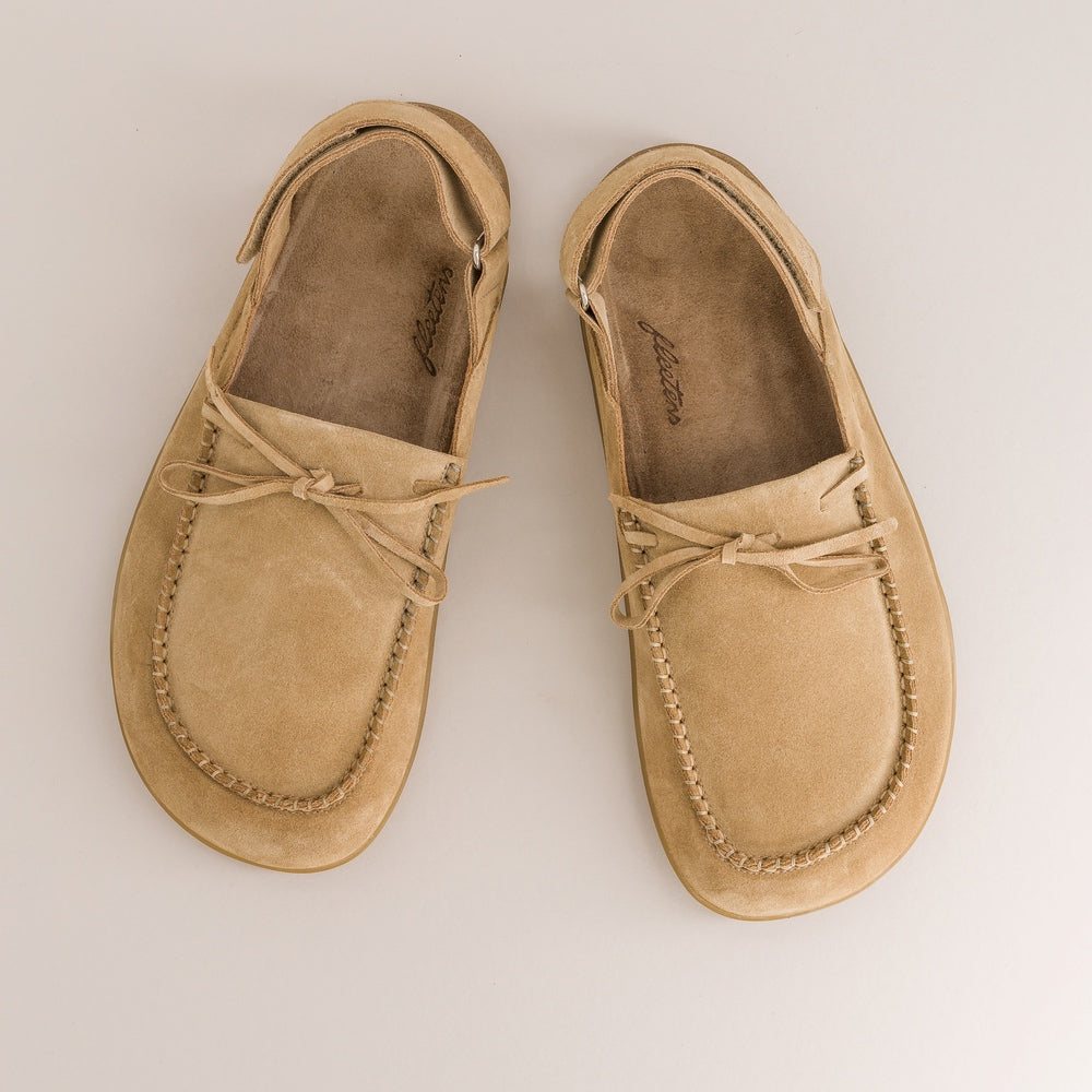 Pair of tan barefoot mules on a light beige background