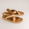 Pair of brown barefoot sandals with gold straps on a light gray background