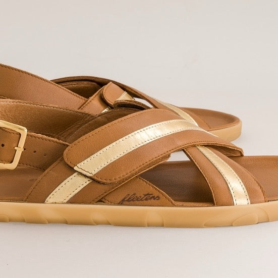 Brown barefoot sandals with gold straps on a light gray background