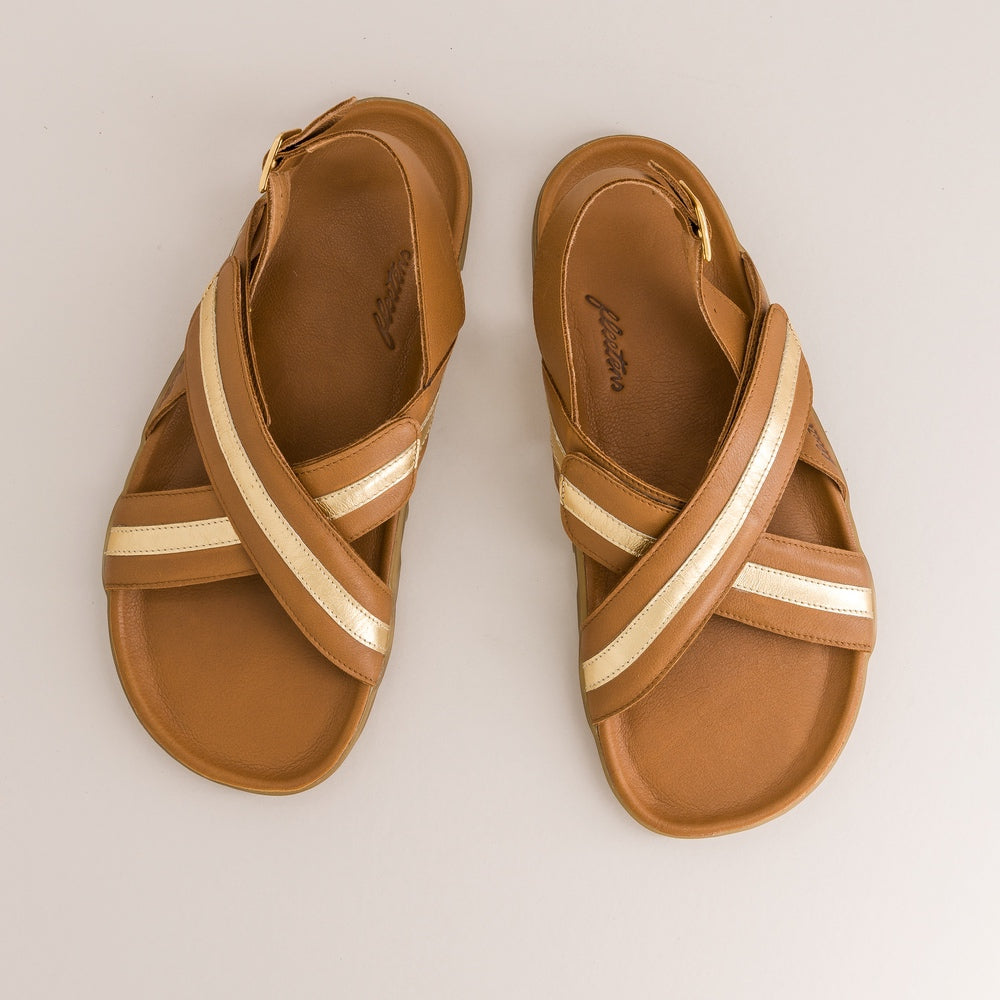 Pair of brown barefoot sandals with gold straps on a light beige background
