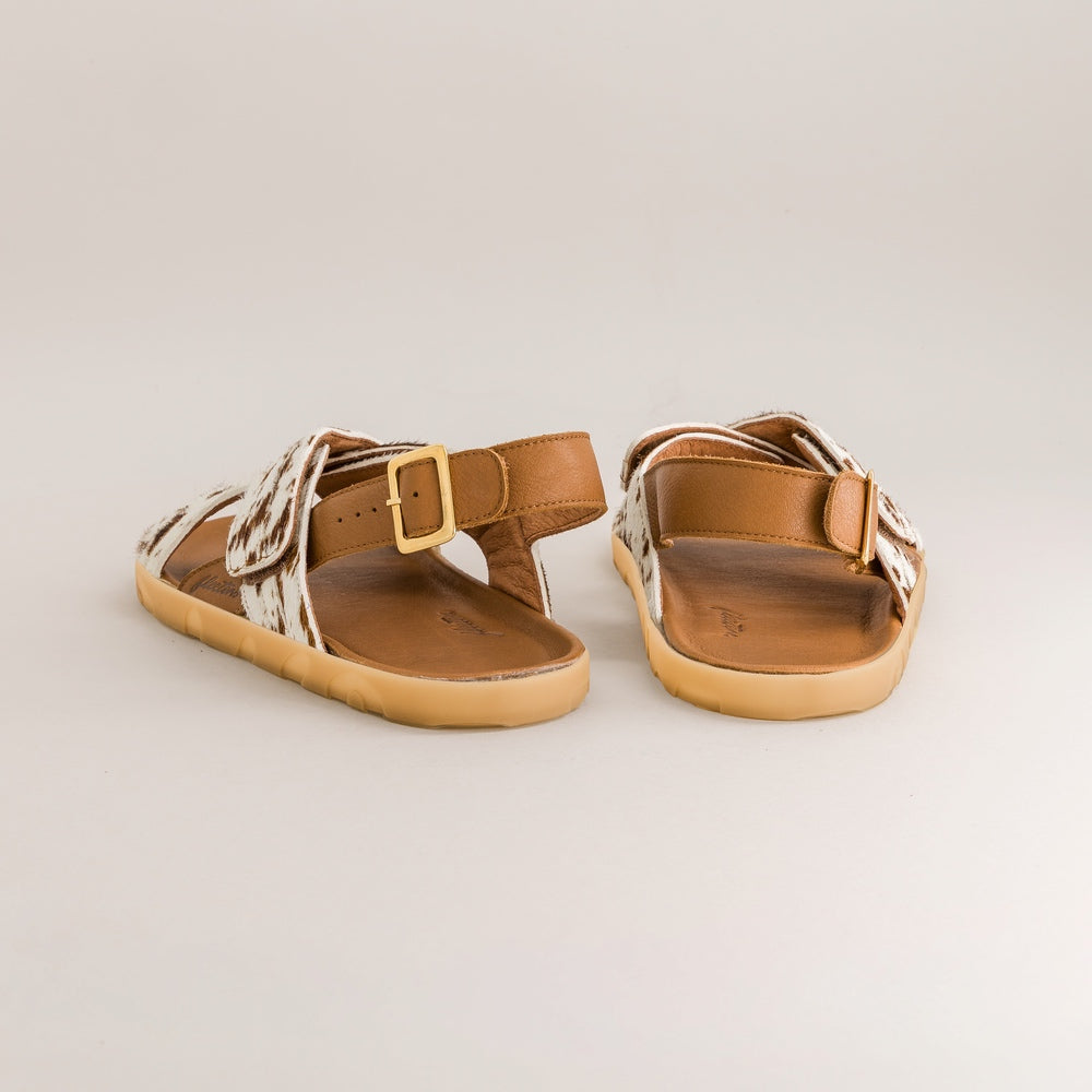 Pair of brown barefoot sandals with gold buckle on a light gray background