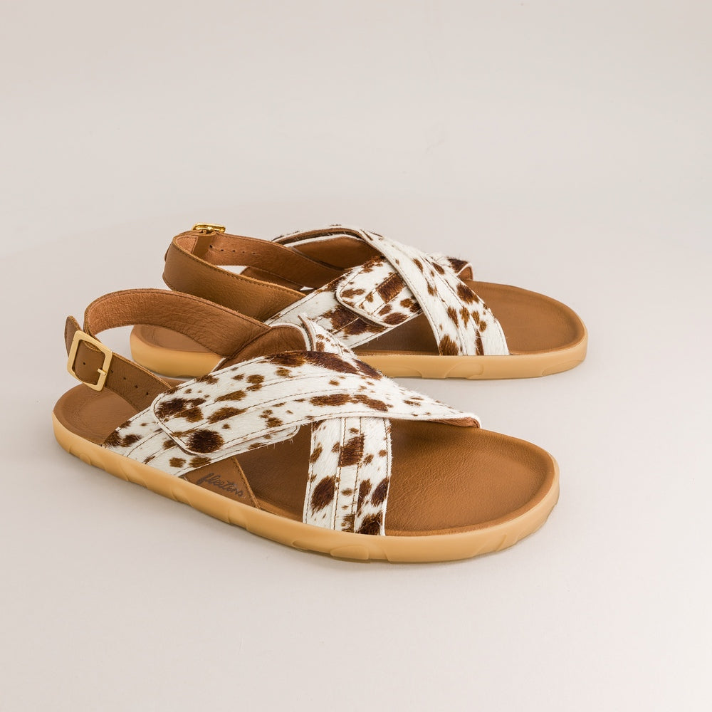 Pair of barefoot sandals with cow print straps on a light gray background