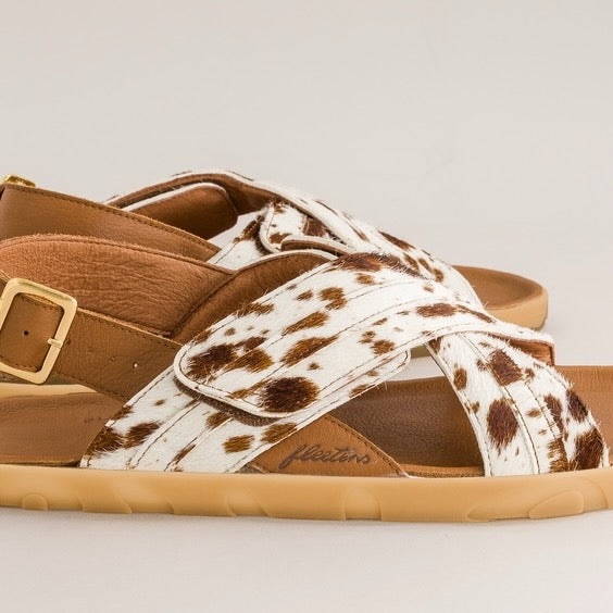 Brown barefoot sandal with cow print strap on a light gray background