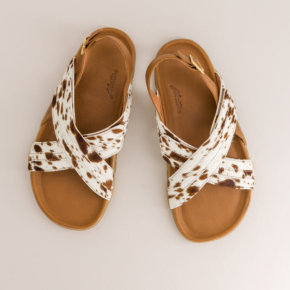 Pair of barefoot sandals with cow print straps on a light gray background