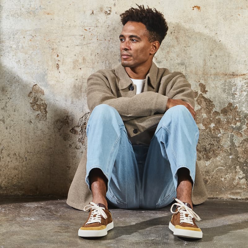 Man seating with jeans, jacket, and Lemon Roble barefoot sneakers