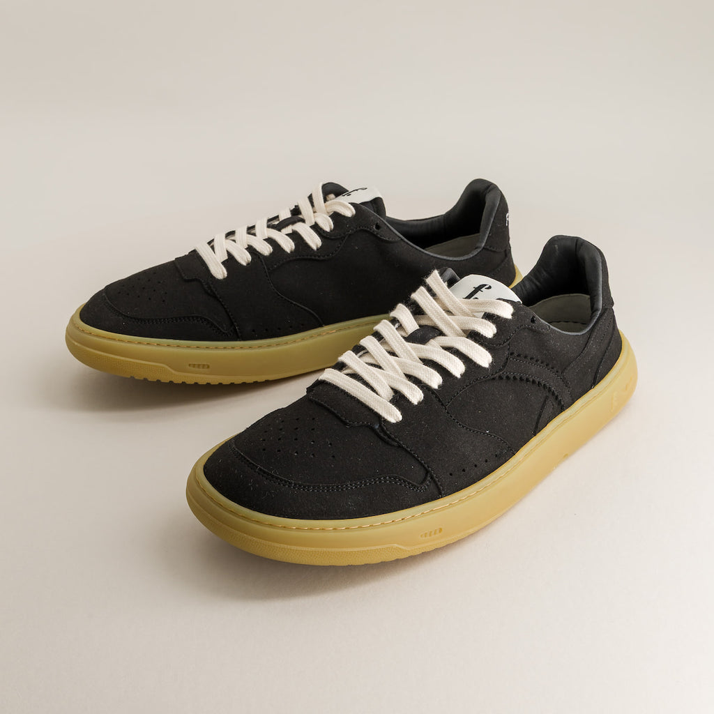 Black barefoot sneakers with white laces on a light gray background