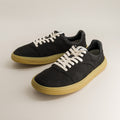 Black barefoot sneakers with white laces on a light gray background