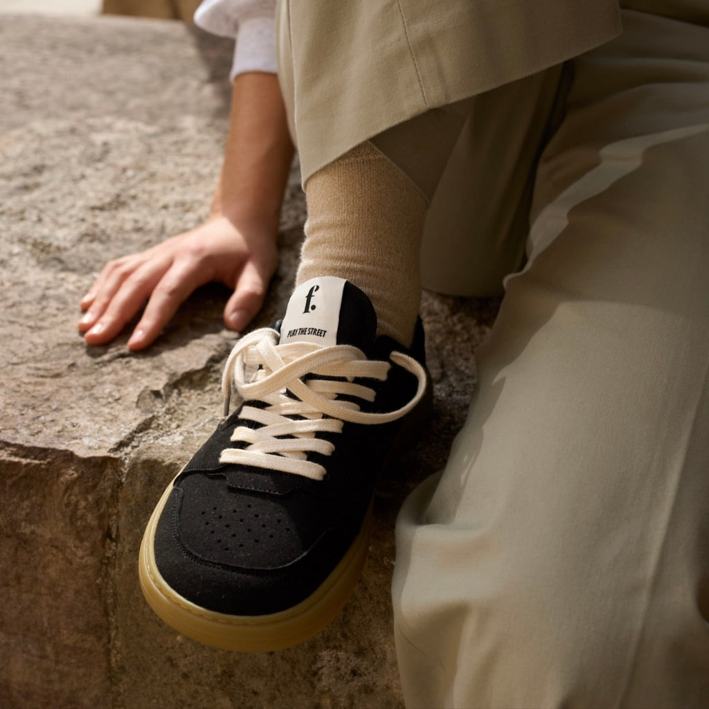 person wearing black barefoot sneakers with white laces