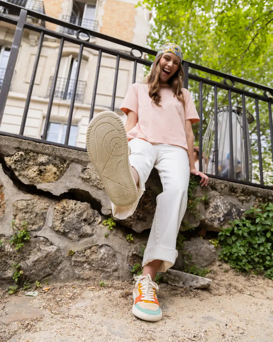 Person sitting on stone steps with a black metal railing and greenery in the background