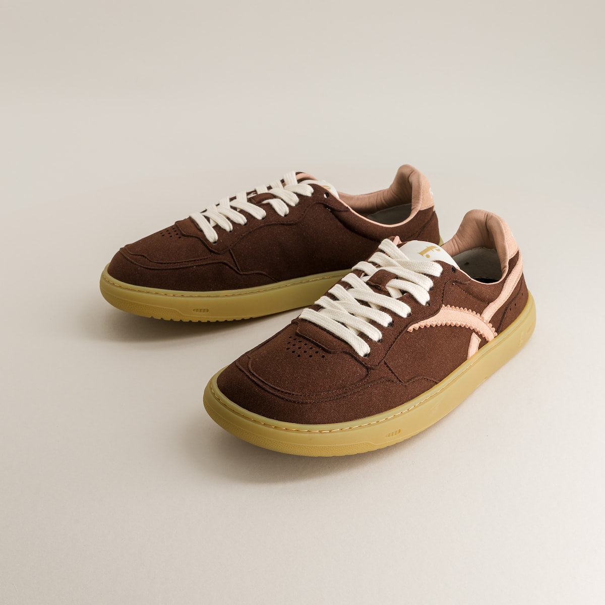 Brown barefoot sneakers with white laces on a light gray background
