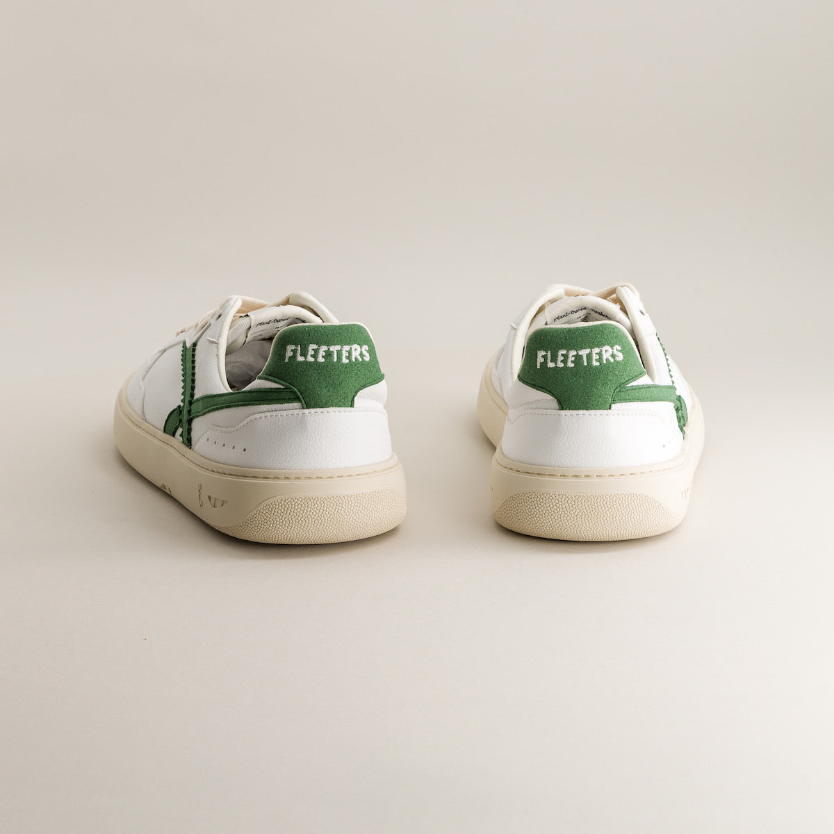 White barefoot sneakers with green accents and 'Fleeters' branding on a light background