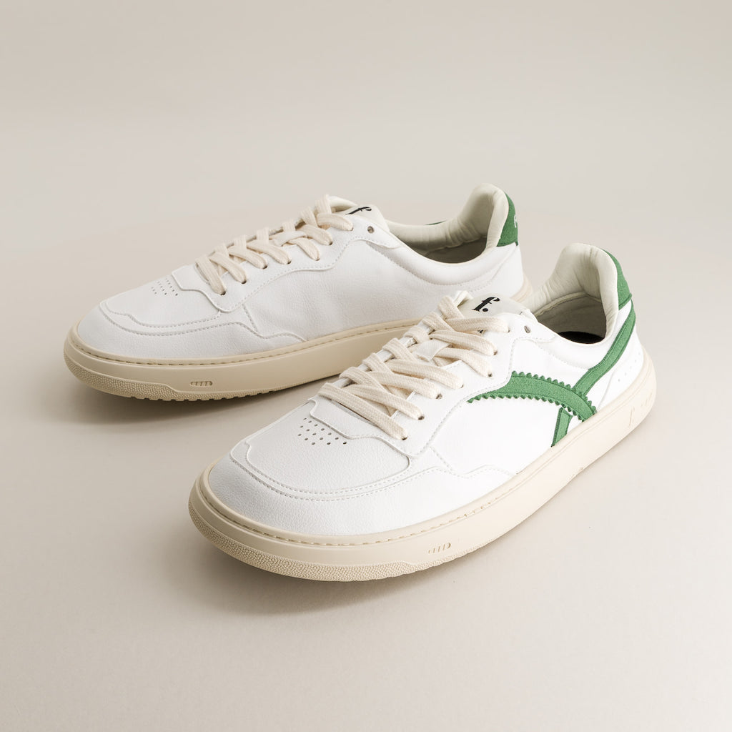 White barefoot sneakers with green accents on a light gray background