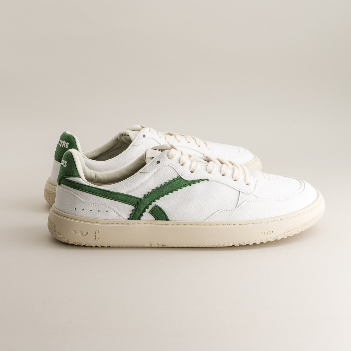 White barefoot sneakers with green accents on a light gray background 