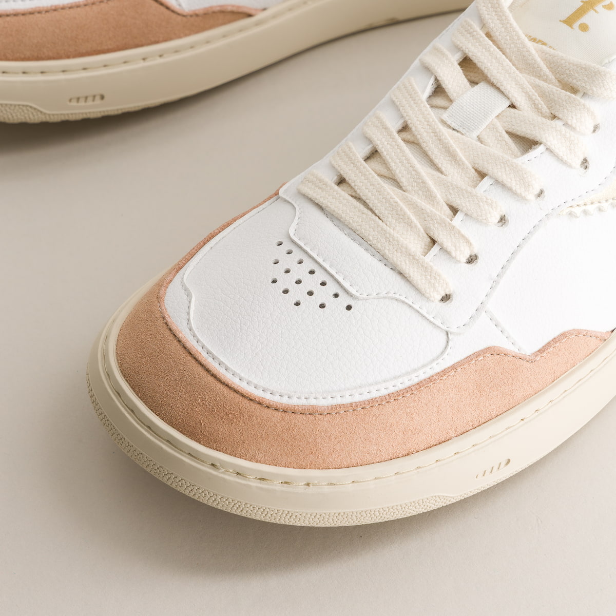 Close-up of a sneaker with white and beige color scheme on a light background