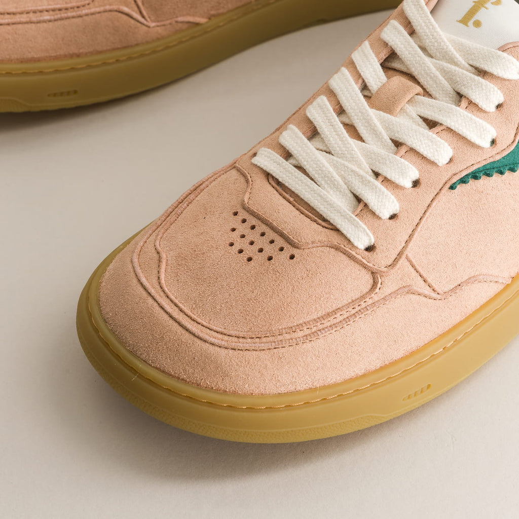 Close-up of a pink sneaker with white laces on a light background