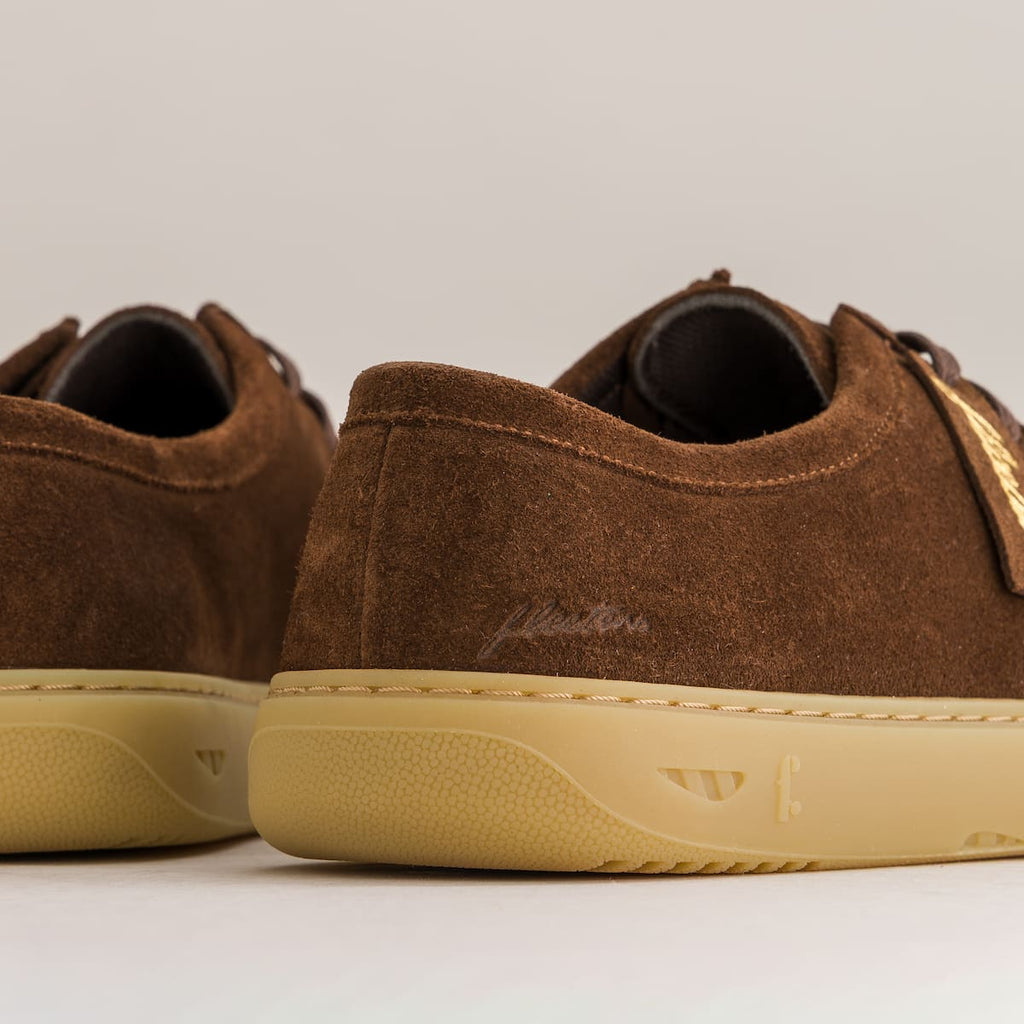 Brown suede shoes with beige soles on a light gray background