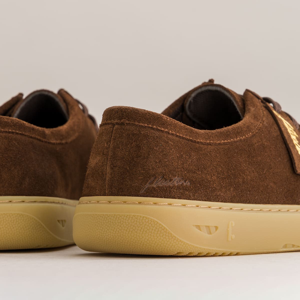 Brown suede shoes with beige soles on a light gray background