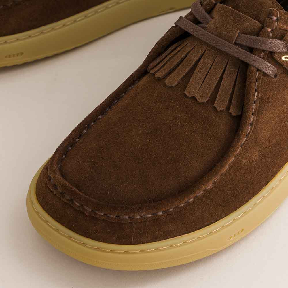 Brown suede loafer with fringes on a light background