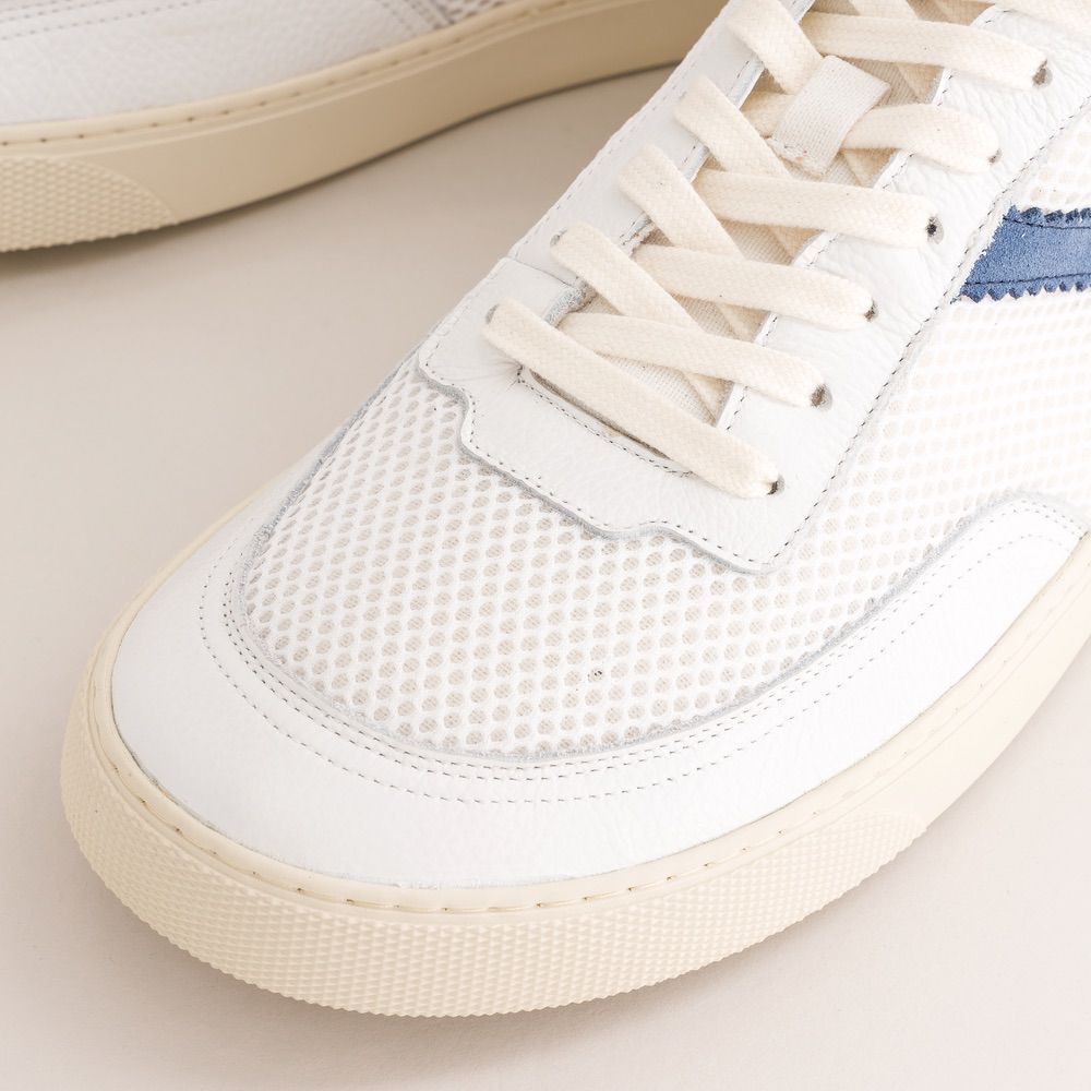Close-up of a white mesh mid-ankle barefoot sneaker with beige laces and sole on a light background