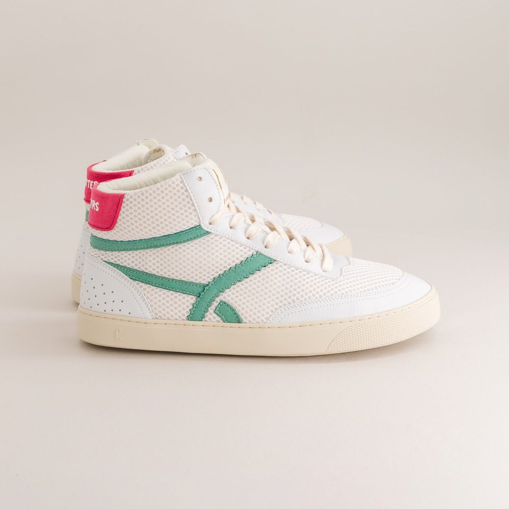 White high-top sneaker with green accents on a beige background