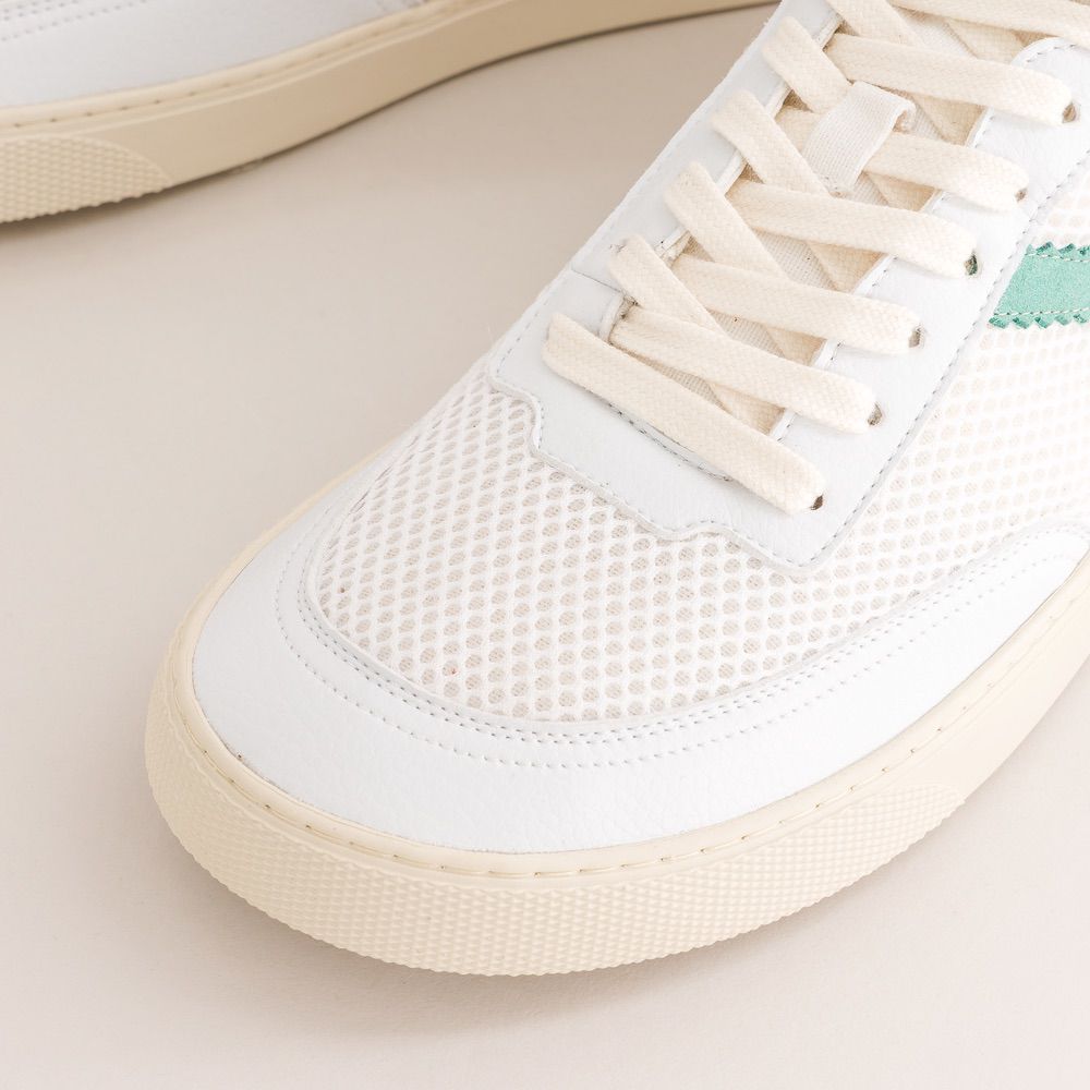 Close-up of a white mesh sneaker with beige sole on a light background