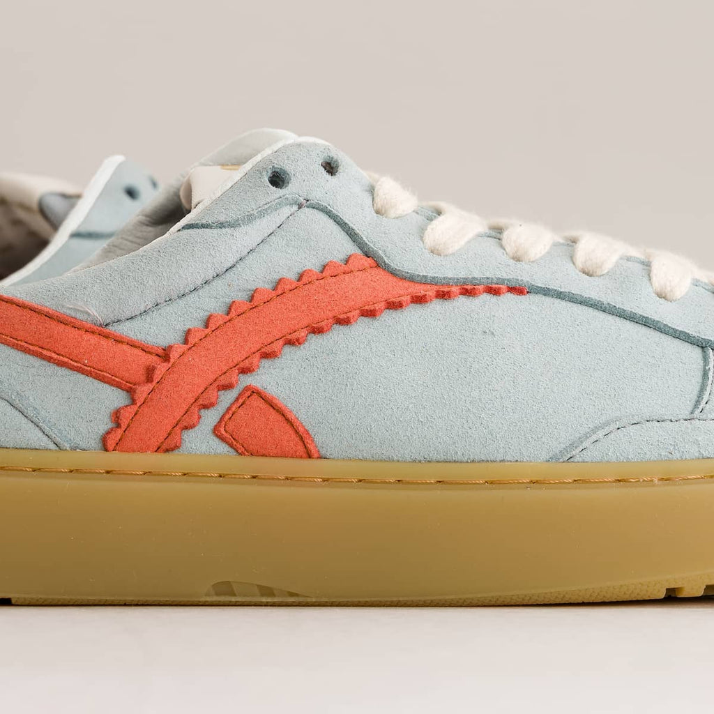Sneaker with light blue upper, orange accents, and yellow sole on a gray background