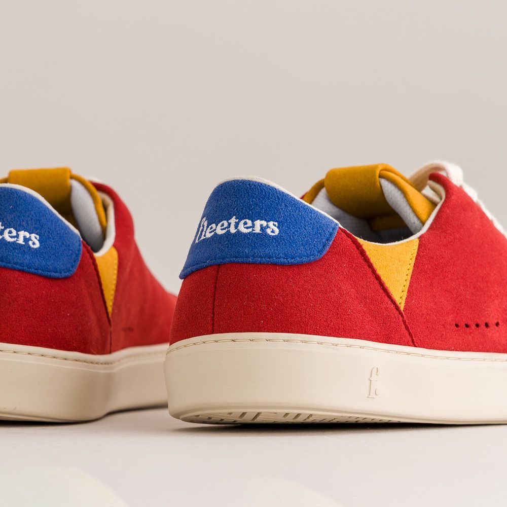 Red sneakers with blue and yellow accents on a light gray background