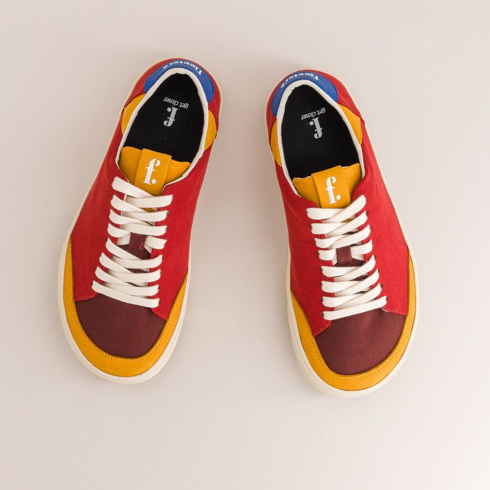 Red and yellow barefoot sneakers with white laces on a light gray background