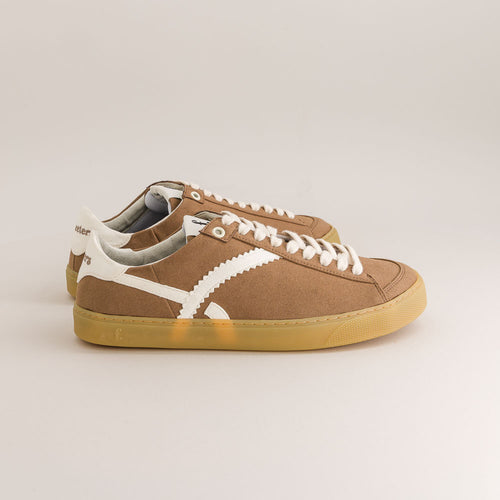 Brown  barefoot sneakers with white laces on a beige background