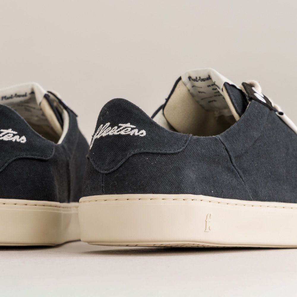 Close-up of black sneakers with beige soles on a light gray background