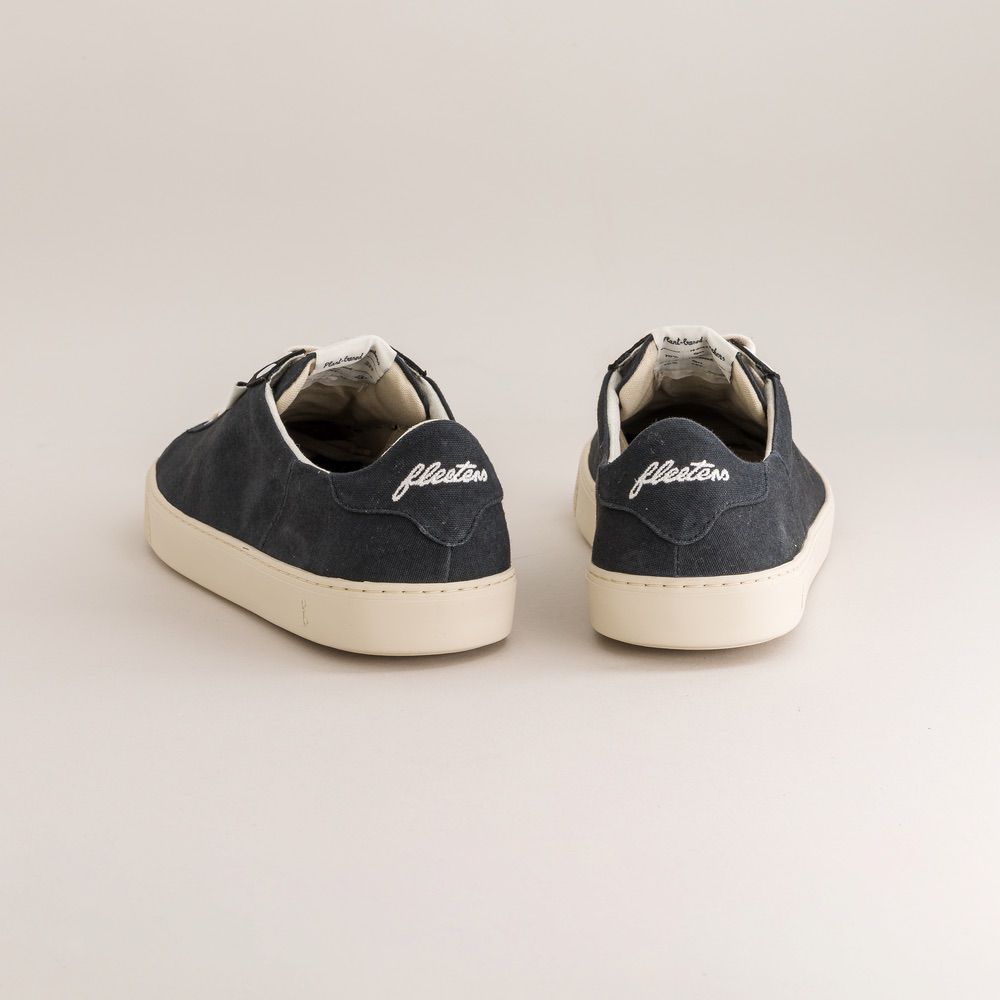 Pair of navy blue sneakers with 'fleeters' branding on a light beige background