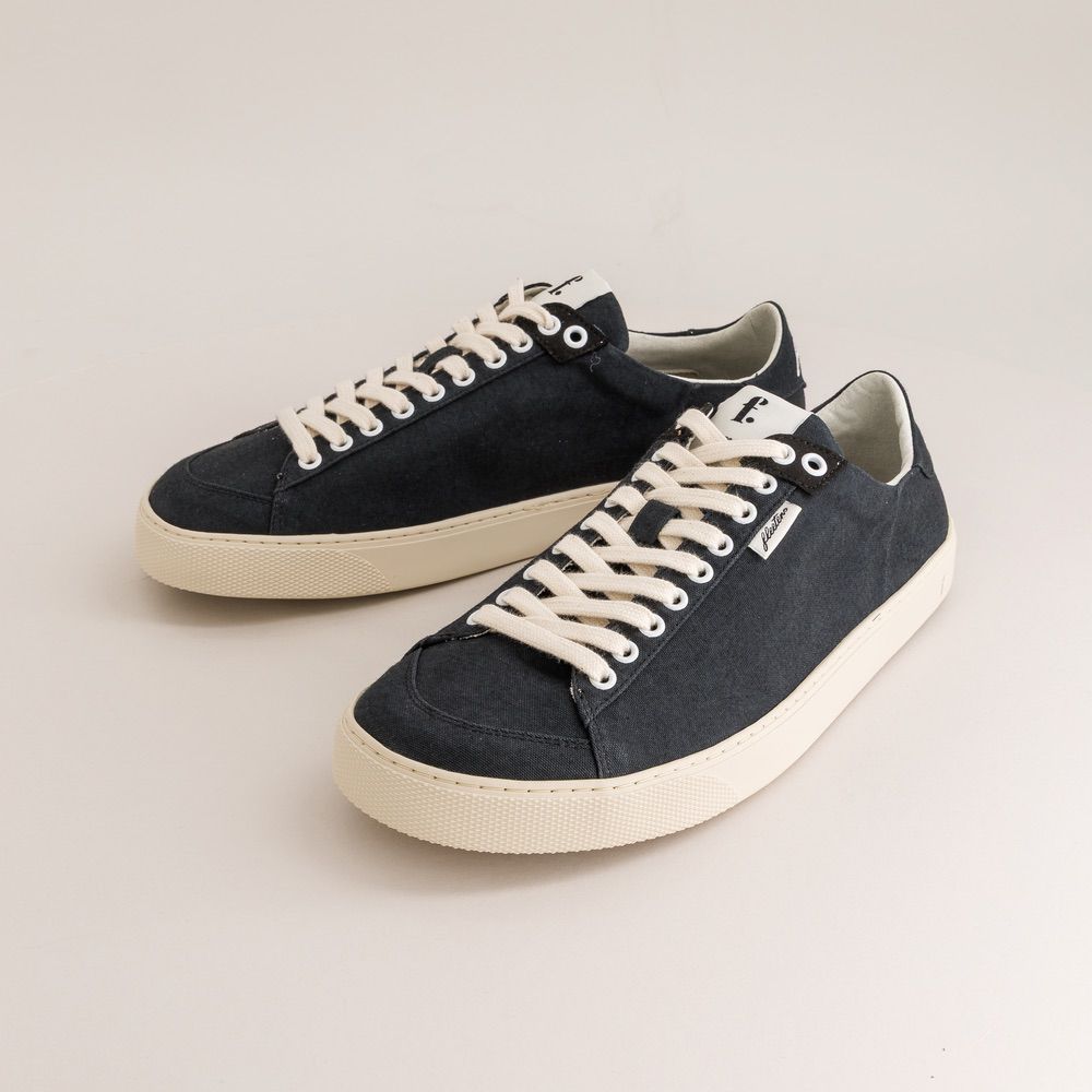 Pair of black barefoot sneakers with white laces on a light gray background