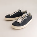 Pair of black barefoot sneakers with white laces on a light gray background