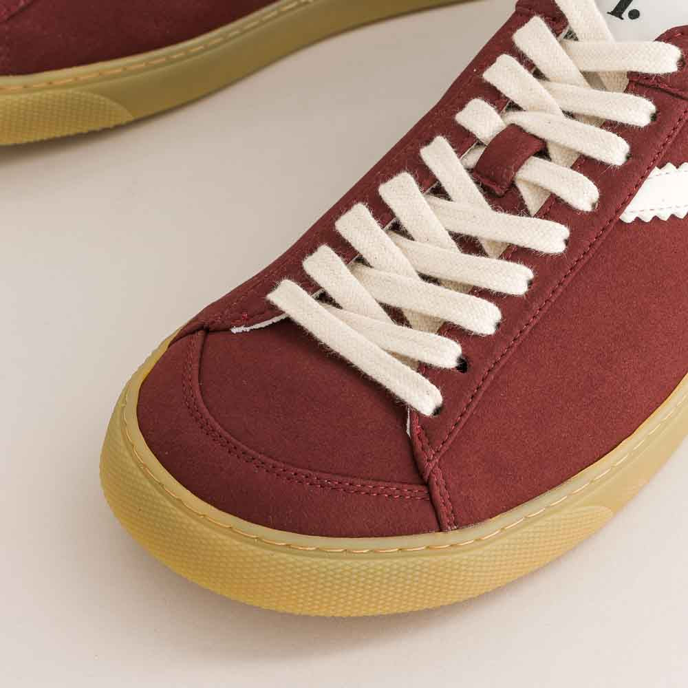 Maroon barefoot sneakers with white laces on a light background