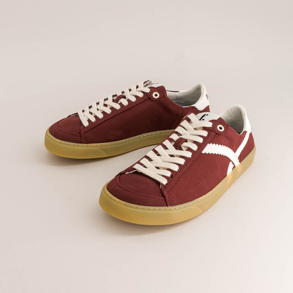 Pair of maroon barefoot sneakers with white laces on a light gray background