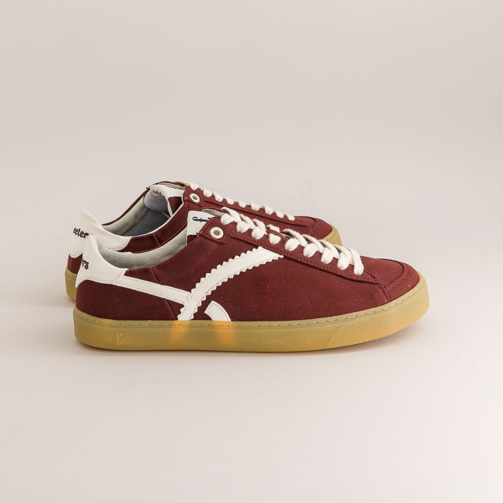 Burgundy barefoot sneakers with white laces and soles on a light gray background