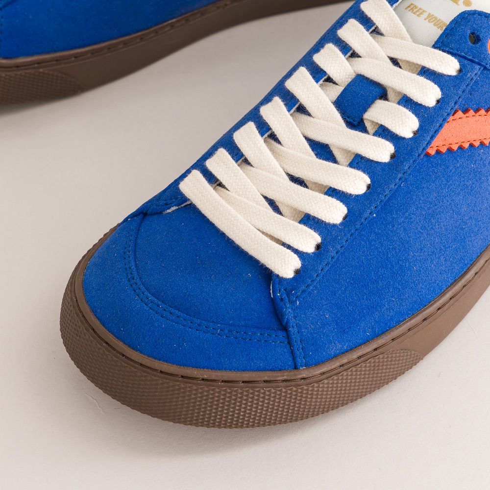 Blue sneaker with white laces on a light background