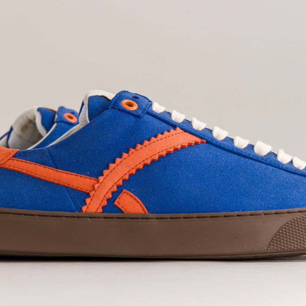 Blue and orange sneaker with white laces on a gray background