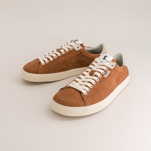 Pair of brown minimalist sneakers with white laces on a light gray background