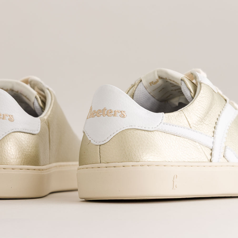 Pair of gold and white sneakers with 'Bleeters' branding on a light background