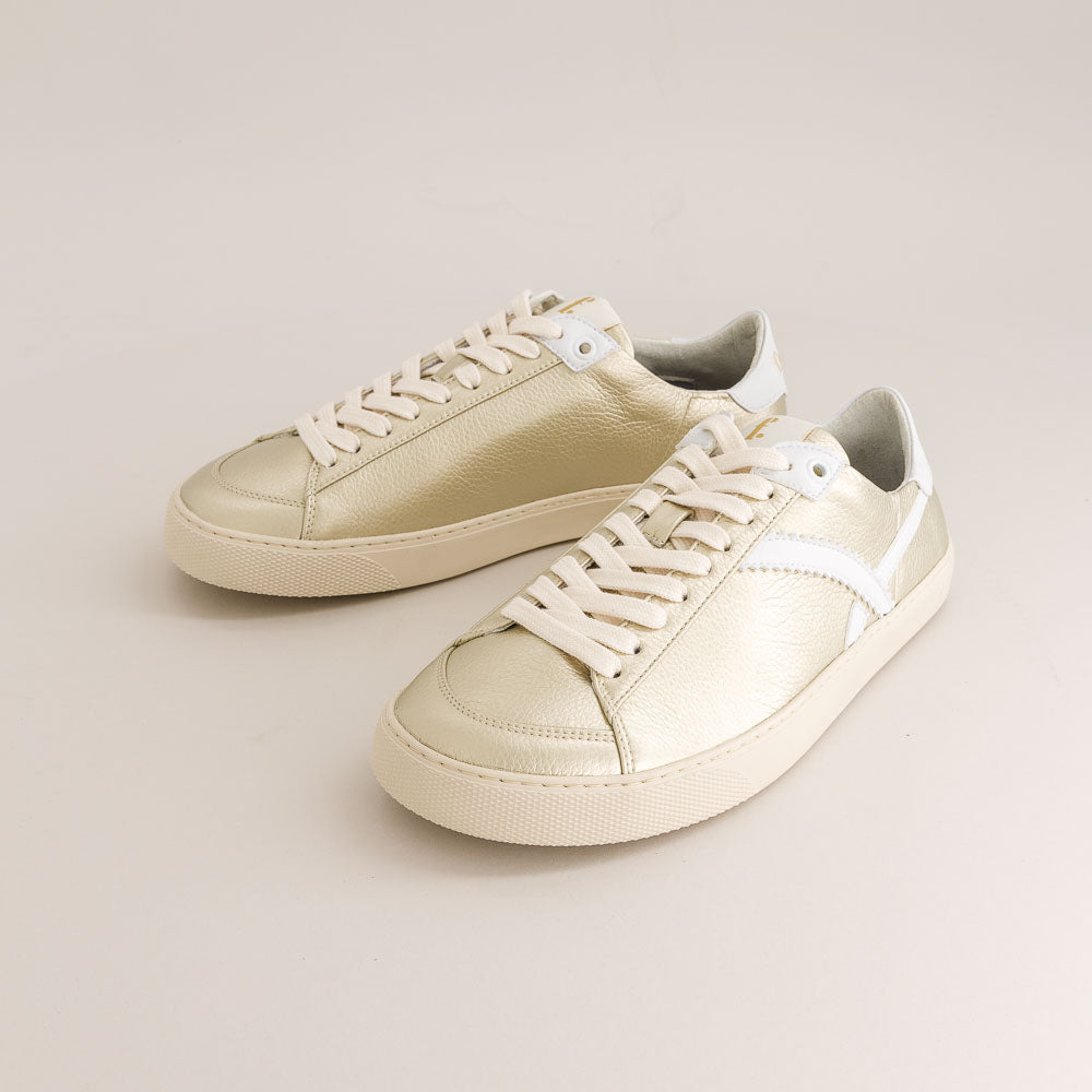 Pair of gold barefoot sneakers with white laces on a light gray background